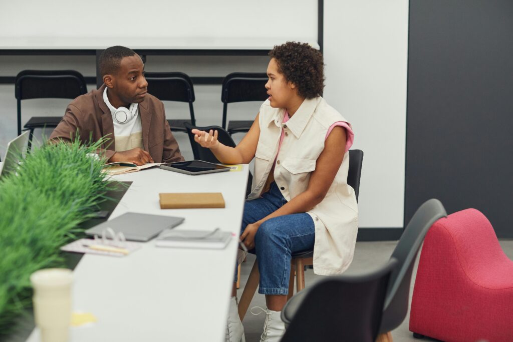 Two colleagues having a discussion in a modern office, fostering teamwork and creativity.