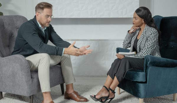 A business conversation between a man and woman in a modern office setting, focusing on engagement and communication.