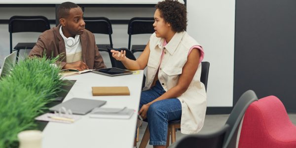 Two colleagues having a discussion in a modern office, fostering teamwork and creativity.